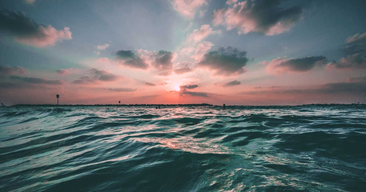Abstract watercolor of a calm sea settling under a softening sunset sky — emotional intensity finding regulation