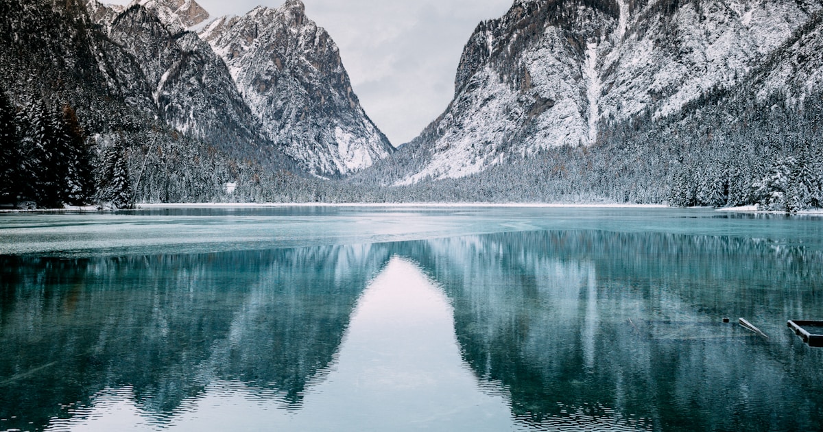 Abstract watercolor of snowy peaks easing down to a calm still lake — the gentle, gradual descent of a careful taper