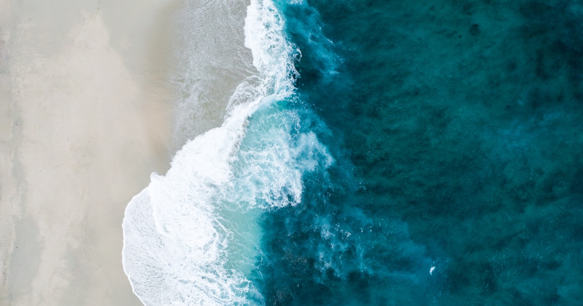 Abstract watercolor of waves spreading thin and flattening across calm sand — cravings losing their power