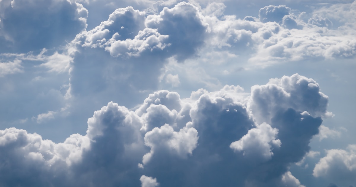 Abstract watercolor of soft white clouds drifting across a clear blue sky — clear lungs and a clear day on the other side of quitting