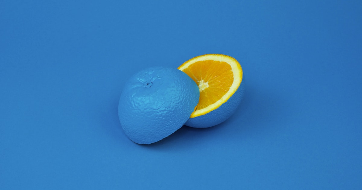 Abstract watercolor of a blue-toned fruit cut open to reveal bright color inside — the hidden struggle beneath a composed surface
